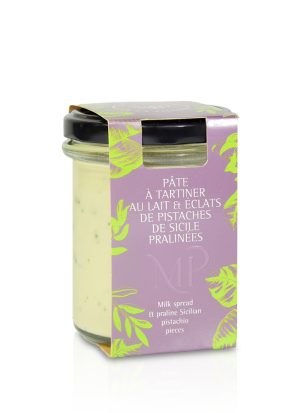 Glass med pistasjkrem fra La Maison de la Pistache. Produktet er merket “Pâte à tartiner au lait & éclats de pistaches de Sicile pralinées”, og inneholder en lys melkekrem med biter av pralinépistasj fra Sicilia. Glass med sort lokk og dekorativt lilla omslag med grønne blader.